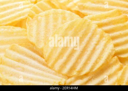 Potato chips pattern. Yellow corrugated salted potato chips as food background. Chips texture, studio photo, close up Stock Photo