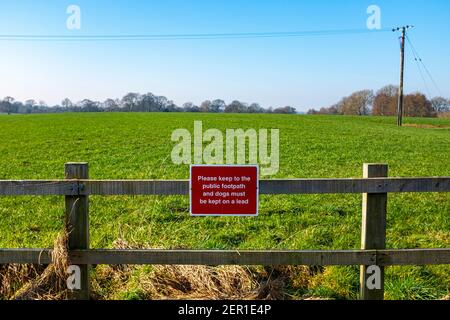 Please keep to the public footpath and dogs must be kept on a lead warning sign in the Cheshire countryside UK Stock Photo