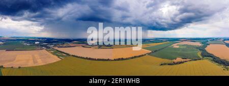 The thunderstorm threatens to destroy the sown wheat on the field. Heavy rain clouds hang over the wheat field. Stock Photo