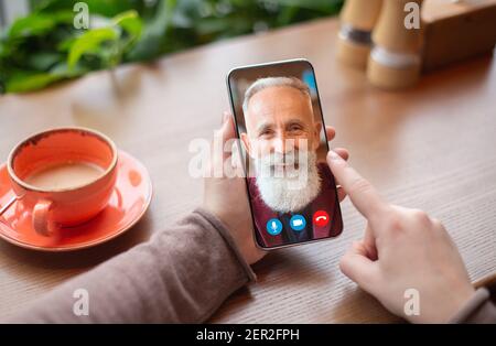 Woman making video call with old man using smartphone Stock Photo