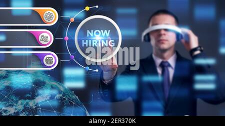 Business, Technology, Internet and network concept. Young businessman working on a virtual screen of the future and sees the inscription: Now hiring Stock Photo