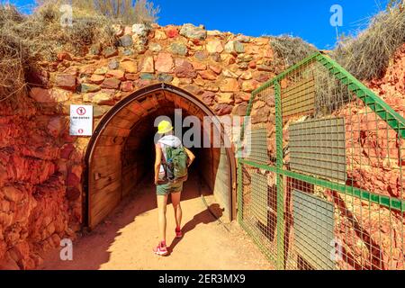 Back of tourist girl with miner's helmet walking inside tunnel cave of Battery Hill Mining Center. Tourism at Tennant Creek in Northern Territory Stock Photo