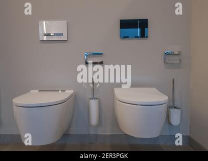 View of two different toilets with matching accessories. Mounted on a light brown wall Stock Photo