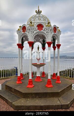 Pretty 19th century Victorian drinking fountain in red and white at Newport on Tay in Fife, Scotland. Tay estuary in the background. Stock Photo