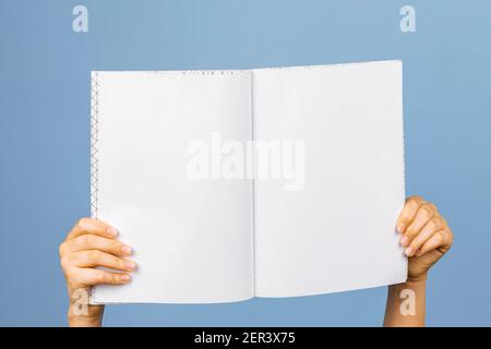 Hands holding blank open notebook over gray background. Empty book, school notebook, diary presentation template Stock Photo