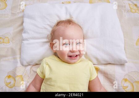 A smiling baby lies on a white pillow. pillowcase mockup. Stock Photo