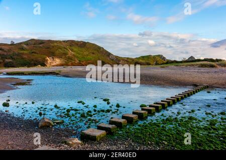 Sandy beach and stepping stones over Pennard Pill at Three Cliffs Bay on the south coast of the Gower Peninsula near Swansea in South Wales UK Stock Photo