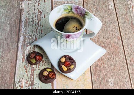 Three small chocolate chip cookies with nuts, next to a cup of coffee. Stock Photo