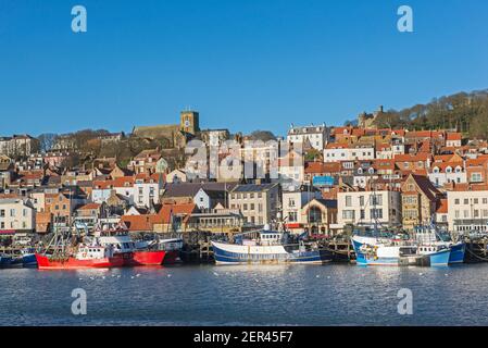 Landscape panorama view of coastal seaside town harbor front with medieval church on hill and fishing boats Stock Photo