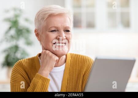Happy old woman using digital tablet in kitchen Stock Photo