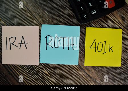 IRA, ROTH, 401k write on sticky notes isolated on Wooden Table. Stock Photo