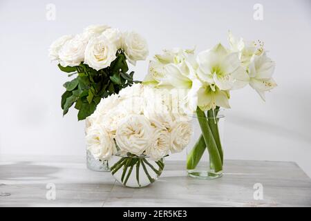 White roses, lily in round vases on the table for a special occasion as a kitchen decoration. Copy space Stock Photo