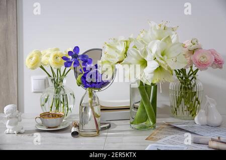 Moscow, Russia - 14 December 2020, A bouquet of white roses in a round glass vase, a bouquet of white amaryllis, a cup of tea, a figurine on the table Stock Photo