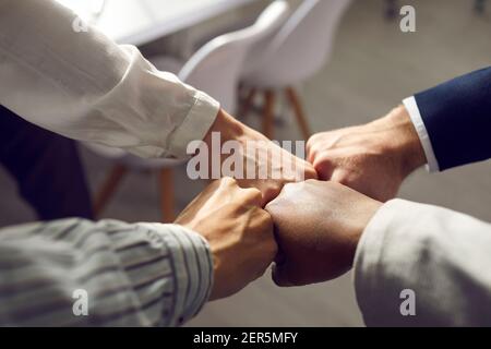 Close up of hands of business partners folding fists together as a symbol of unity. Stock Photo