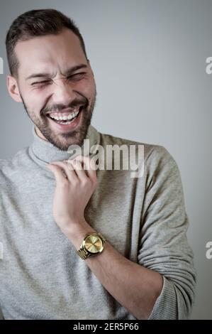 Portrait of a young man with a short beard that laughs cheerfully during a conversation Stock Photo
