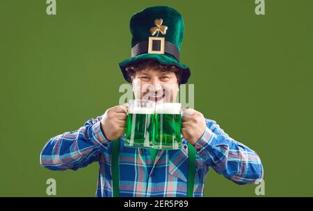 Funny excited man celebrating Saint Patrick's Day and drinking green beer from two mugs Stock Photo