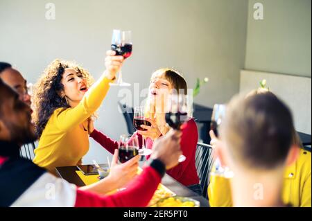 Group of multiracial friends cheering with red wine in trendy winery bar - Happy people drinking and having fun at pub restaurant  - Party and lifesty Stock Photo
