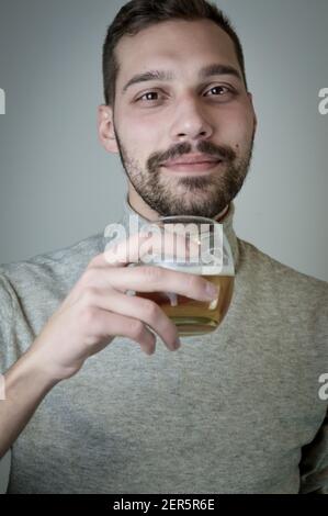Portrait of a young man with a short beard who drinks a glass of beer Stock Photo