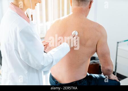 Doctor using stethoscope to check lung function of man Stock Photo