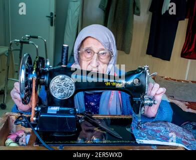 Arabic muslim old woman using old sewing machine Stock Photo