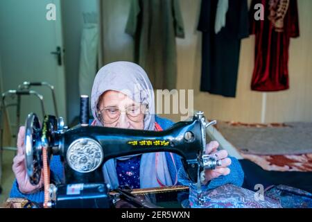 Arabic muslim old woman using old sewing machine Stock Photo