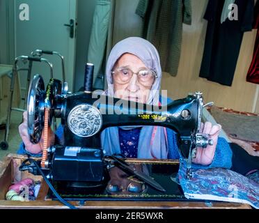 Arabic muslim old woman using old sewing machine Stock Photo