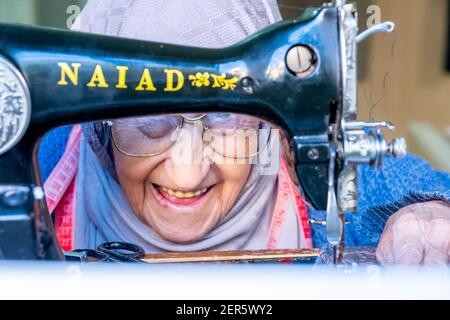 Arabic muslim old woman using old sewing machine Stock Photo