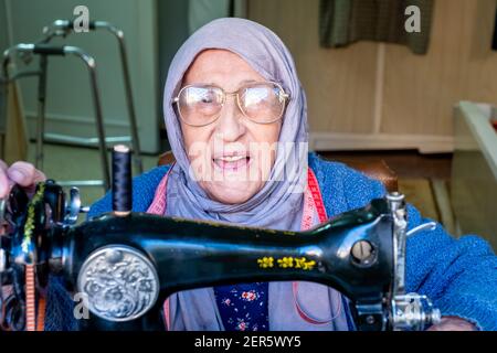 Arabic muslim old woman using old sewing machine Stock Photo