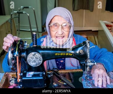 Arabic muslim old woman using old sewing machine Stock Photo