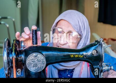 Arabic muslim old woman using old sewing machine Stock Photo