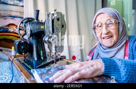 Arabic muslim old woman using old sewing machine Stock Photo