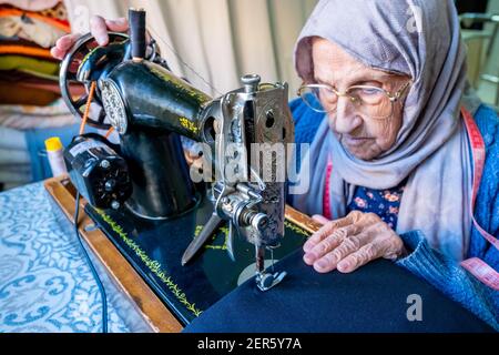 Arabic muslim old woman using old sewing machine Stock Photo