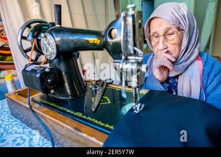 Arabic muslim old woman using old sewing machine Stock Photo