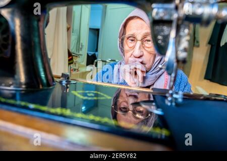 Arabic muslim old woman using old sewing machine Stock Photo