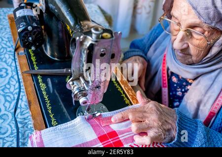 Arabic muslim old woman using old sewing machine Stock Photo