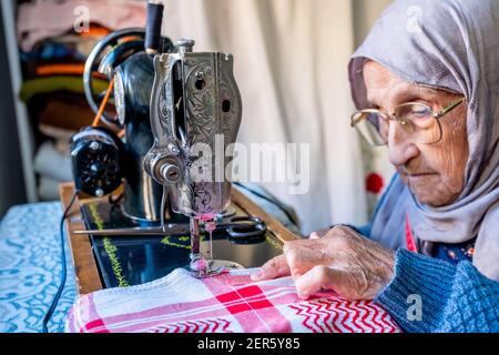 Arabic muslim old woman using old sewing machine Stock Photo