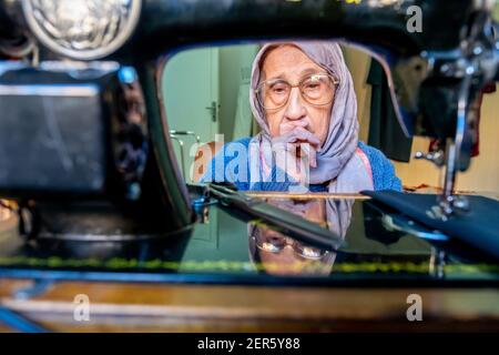 Arabic muslim old woman using old sewing machine Stock Photo