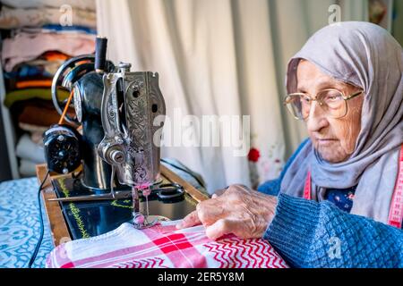 Arabic muslim old woman using old sewing machine Stock Photo