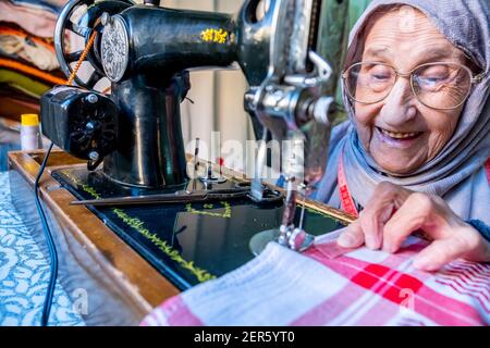 Arabic muslim old woman using old sewing machine Stock Photo