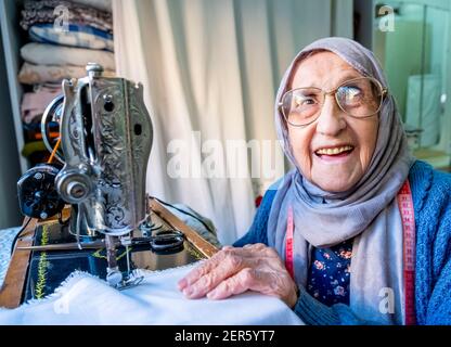 Arabic muslim old woman using old sewing machine Stock Photo