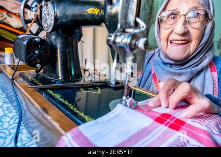 Arabic muslim old woman using old sewing machine Stock Photo