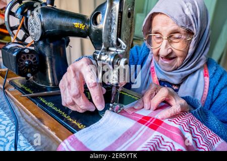 Arabic muslim old woman using old sewing machine Stock Photo