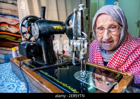 Arabic muslim old woman using old sewing machine Stock Photo