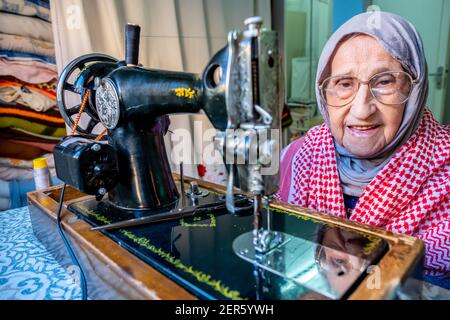 Arabic muslim old woman using old sewing machine Stock Photo