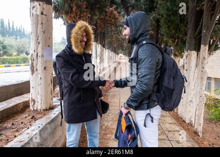 Happy muslim friends shaking hands at university Stock Photo