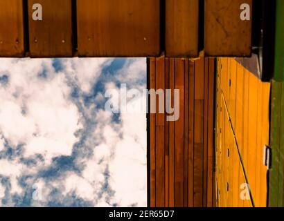 Abstract image of a blue sky with clouds, wooden yellow roof and wall Stock Photo