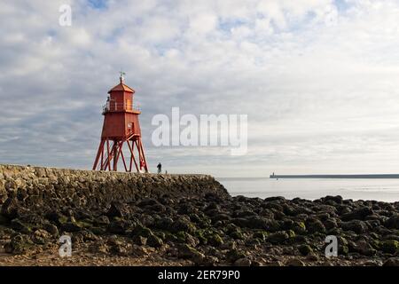 The bright red painted Herd Groyne Lighhouse stands in the mouth of the River Tyne at Littlehaven, South Shields in Tyne and Wear. Stock Photo