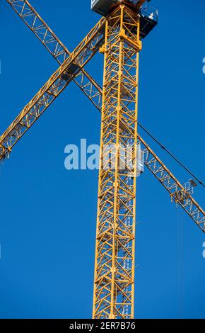 Yellow cranes on a construction site contrasted against a blue sky Stock Photo
