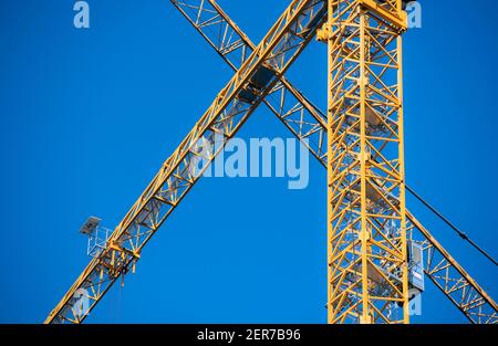 Yellow cranes on a construction site contrasted against a blue sky Stock Photo