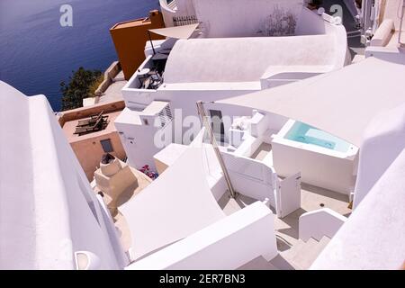 Santorini, Greece - September 11, 2017: op view from above of Santorini villas. Image of small houses with blue water swimming pool on white terrace a Stock Photo